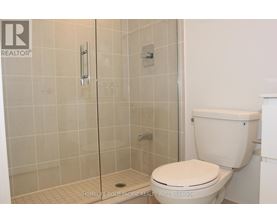 A white toilet in a bathroom with a glass shower door.