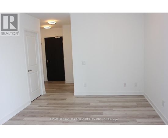 A room with a wooden floor and white walls, with a door on the left and a wall on the right.