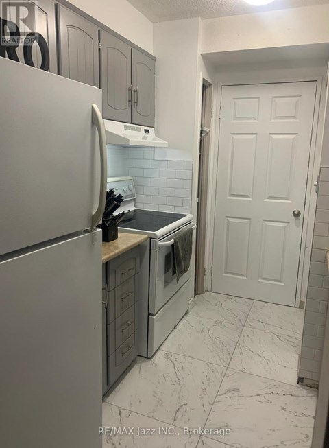 A kitchen with a white refrigerator and a white door.