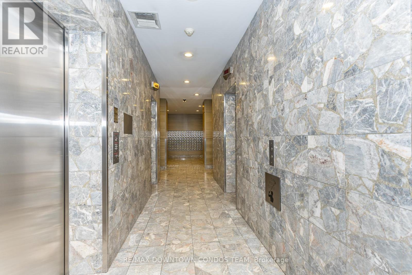 A hallway with a stone wall and a metal door.