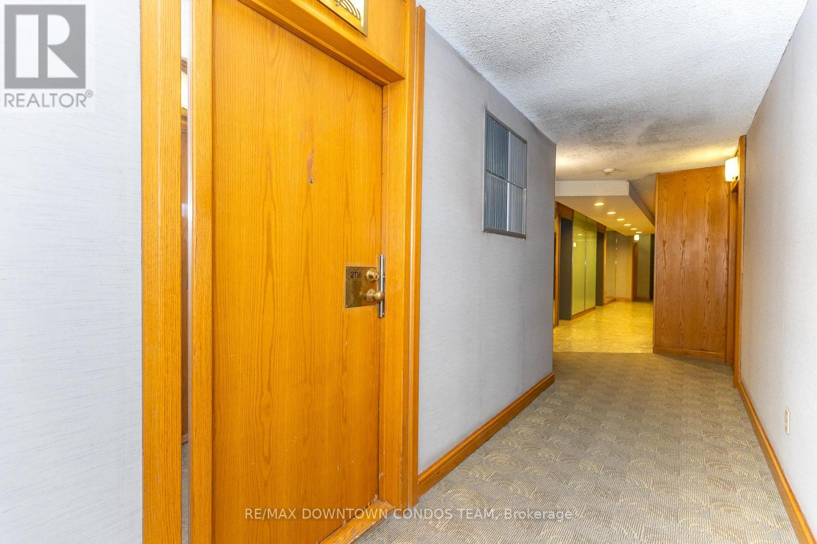 A hallway with a wooden door and carpeted floor.