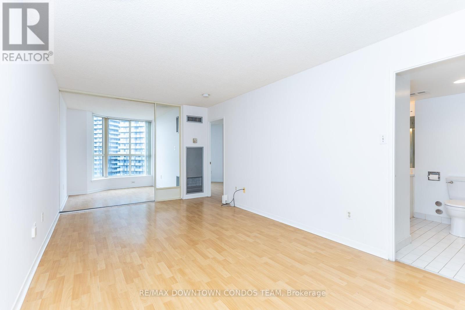 A spacious room with wooden flooring and white walls.