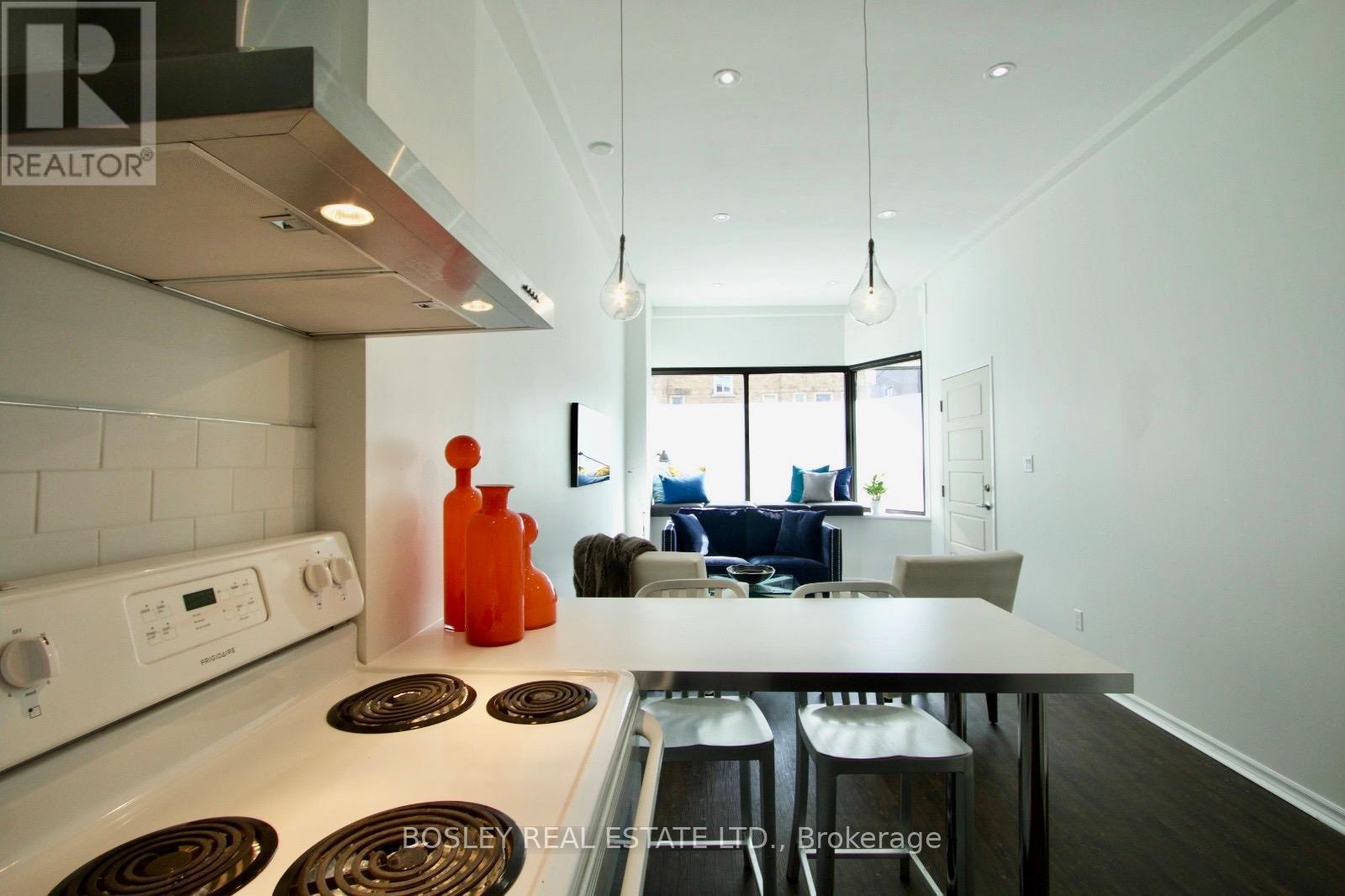 A modern kitchen with a white stove top oven and a dining table with chairs.