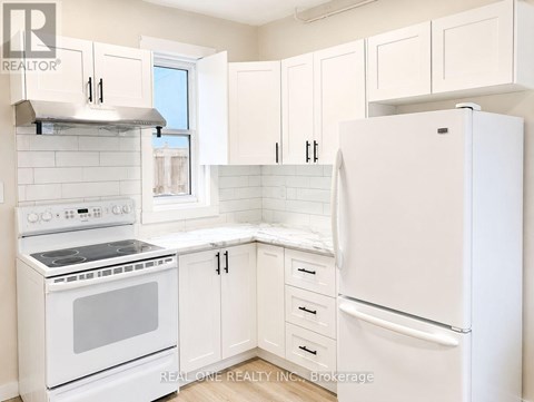 A white kitchen with a stove, oven, and refrigerator.