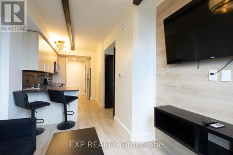 A modern living room with black furniture and a flat screen TV mounted on the wall.