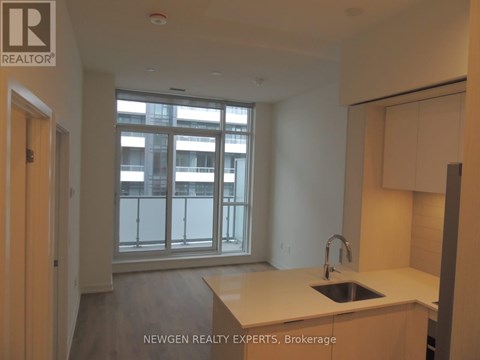 A kitchen with a sink and a window overlooking a balcony.