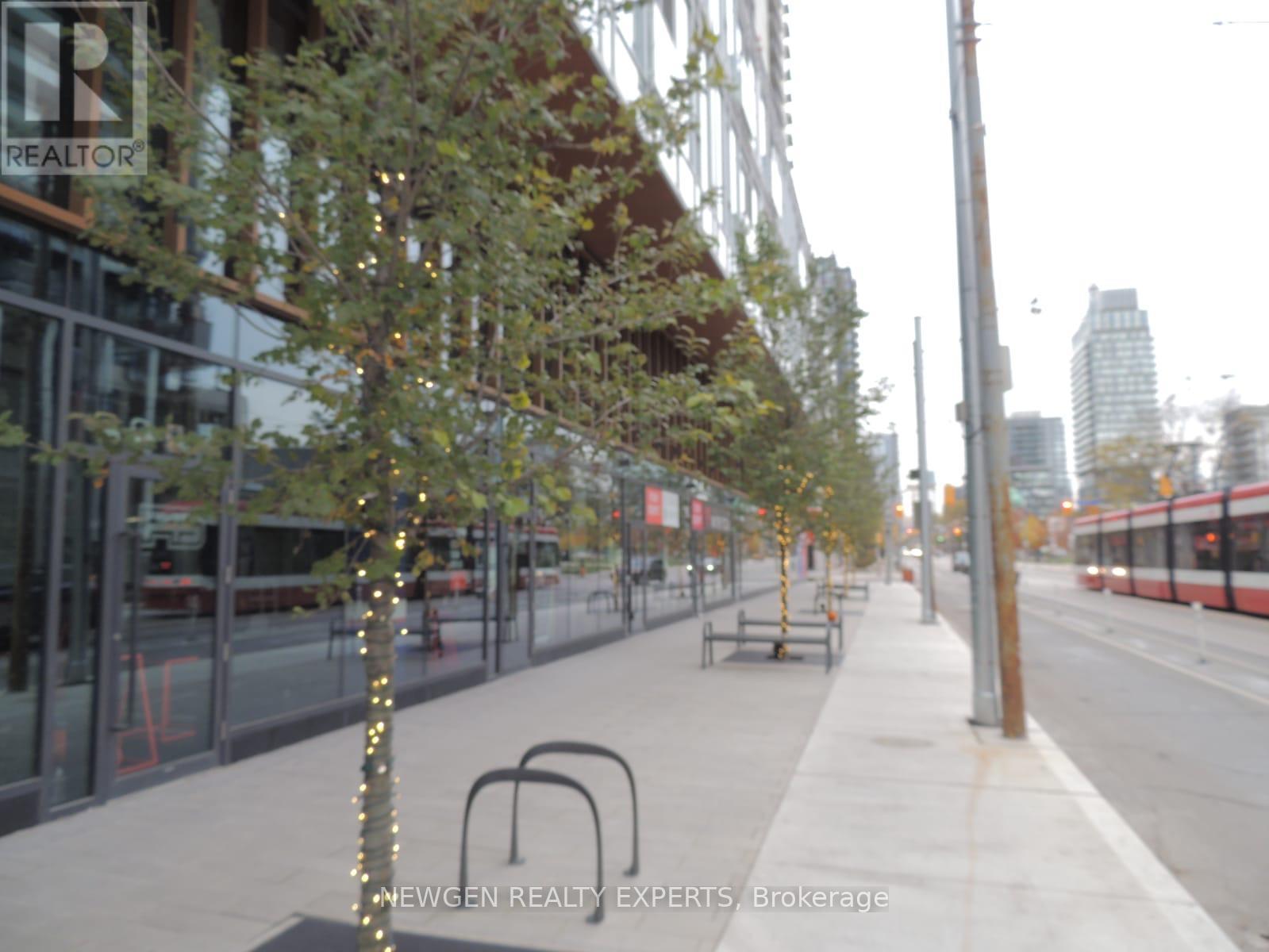 A tree with lights on it is in the middle of a sidewalk.