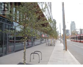 A tree with lights on it is in the middle of a sidewalk.