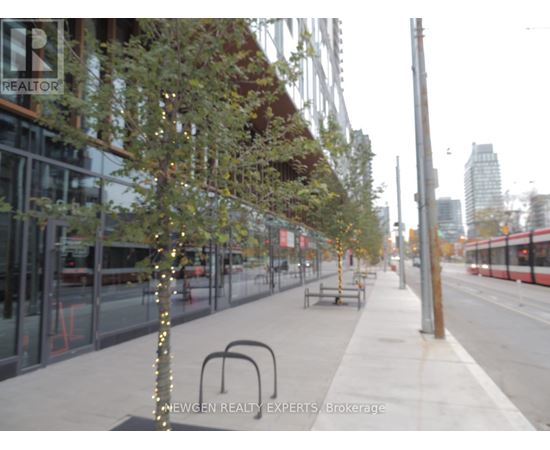 A tree with lights on it is in the middle of a sidewalk.