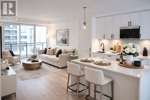 A well-lit, modern kitchen and living room with white furniture and decor.