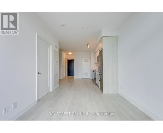 A spacious, empty room with white walls and a wooden floor.
