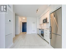 A kitchen with white cabinets and a refrigerator.
