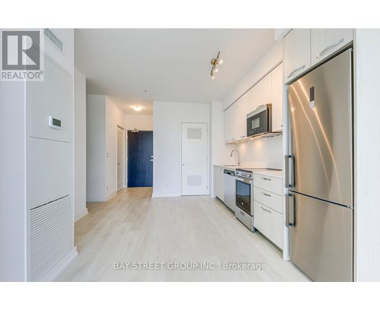 A kitchen with white cabinets and a refrigerator.