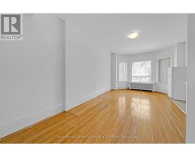 A spacious room with wooden flooring and white walls.