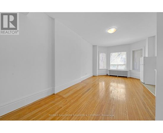 A spacious room with wooden flooring and white walls.