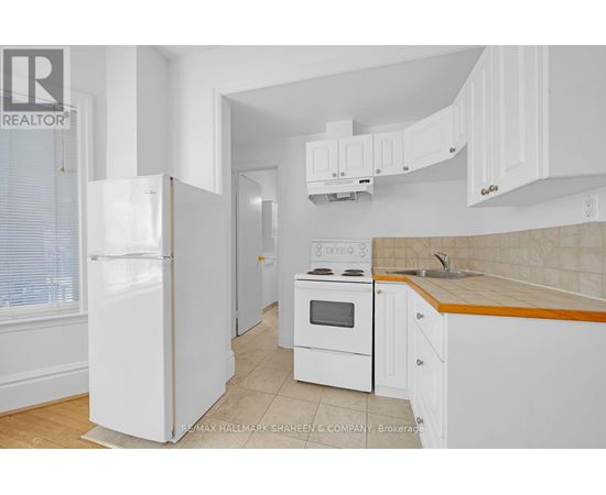 A white kitchen with a refrigerator, oven, and cabinets.