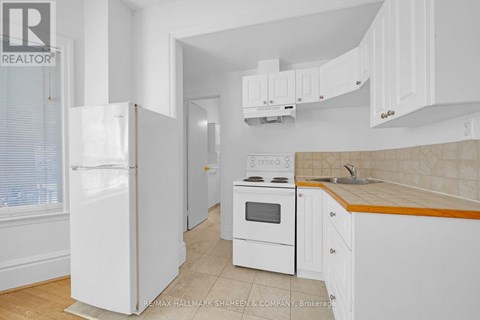 A white kitchen with a refrigerator, oven, and cabinets.