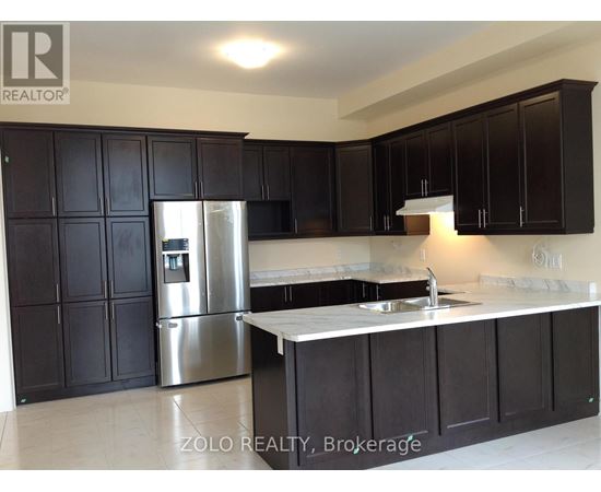 A kitchen with black cabinets and a stainless steel refrigerator.