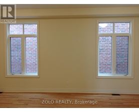 A room with two windows showing brick walls outside.