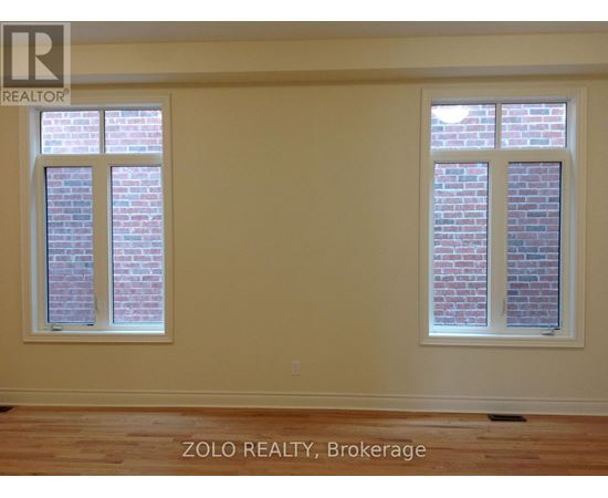A room with two windows showing brick walls outside.