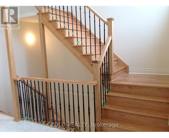 A wooden staircase with a black railing.