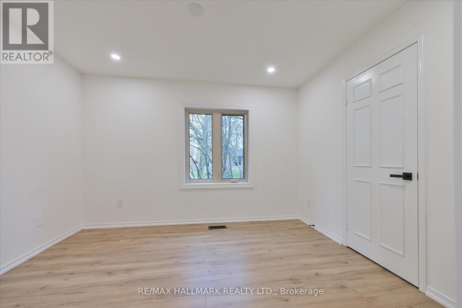 A room with a white door and a window with a view of trees outside.