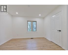 A room with a white door and a window with a view of trees outside.