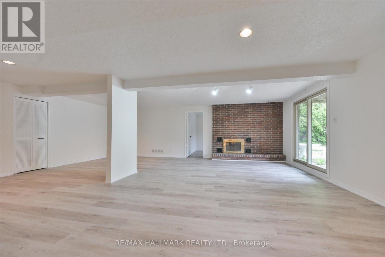 A spacious living room with a fireplace and a large window.