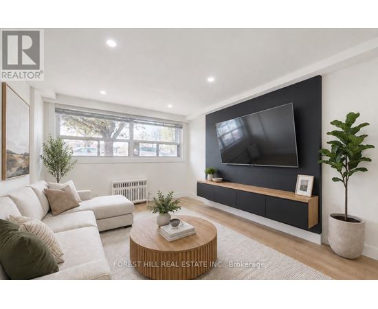 A modern living room with a white sofa, a wooden coffee table, and a flat-screen TV mounted on the wall.