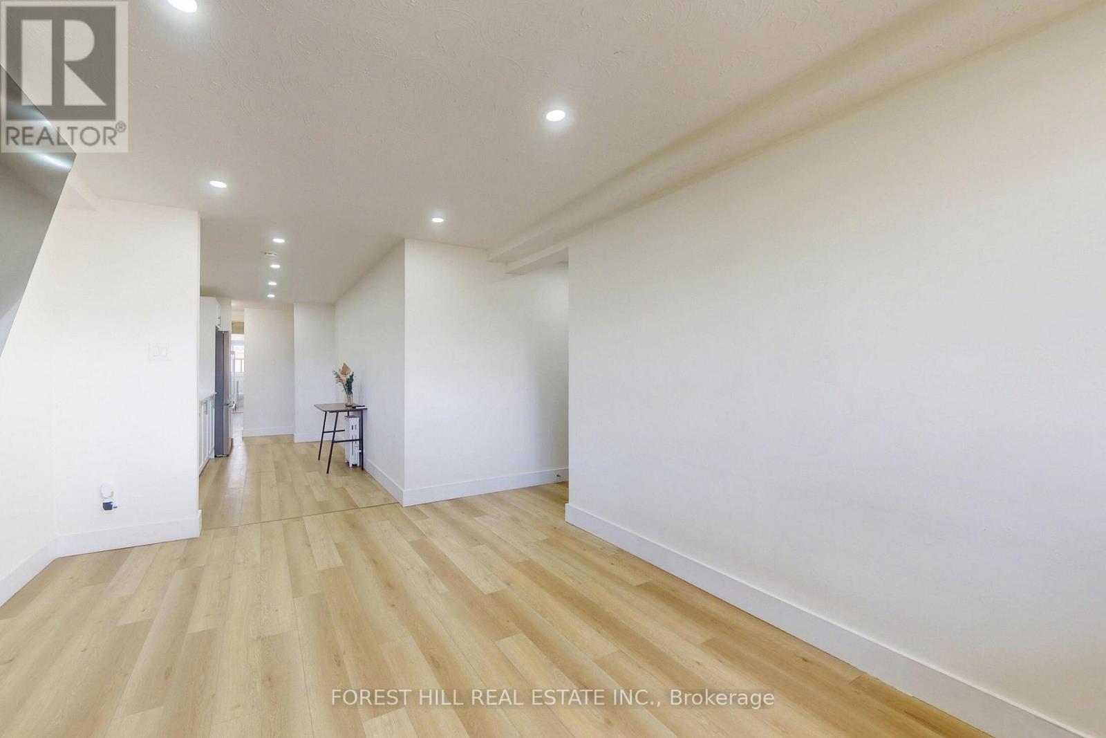A spacious room with wooden flooring and white walls.