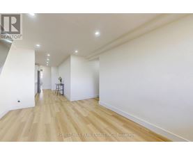 A spacious room with wooden flooring and white walls.