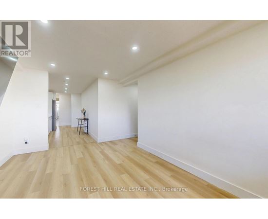 A spacious room with wooden flooring and white walls.