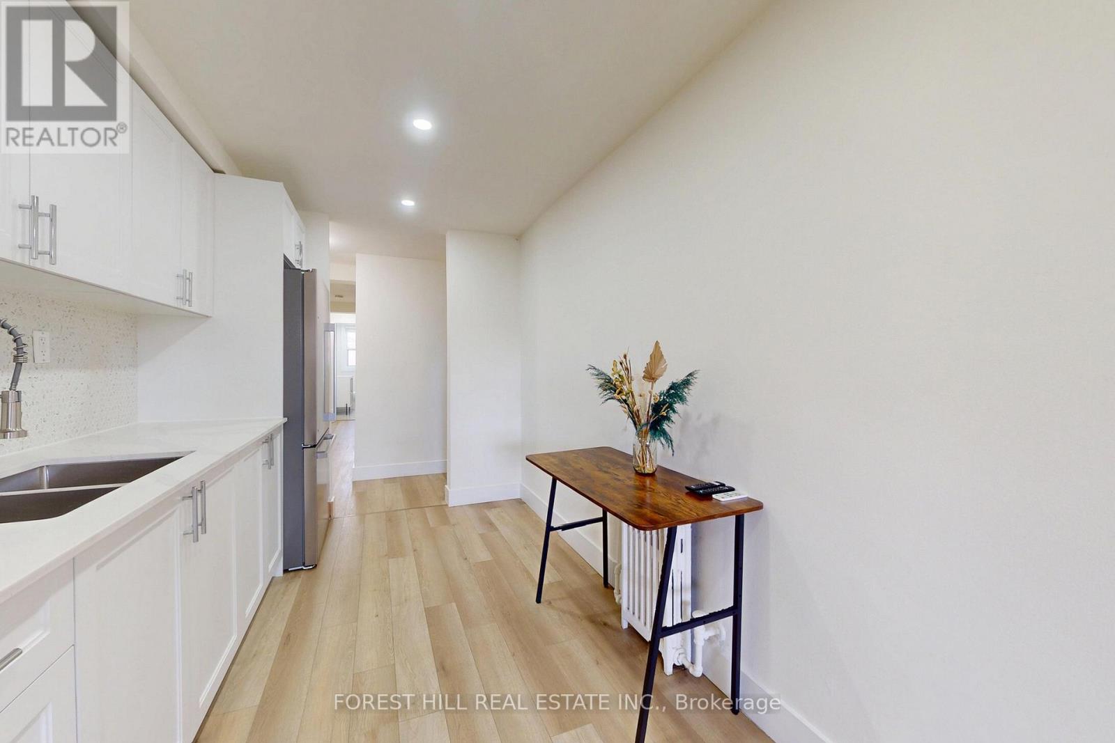 A kitchen with white cabinets and a wooden table with a vase of flowers on it.