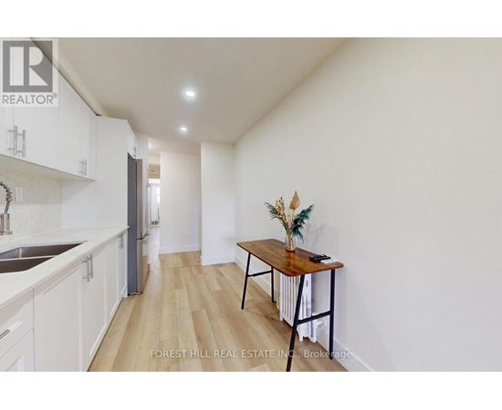 A kitchen with white cabinets and a wooden table with a vase of flowers on it.
