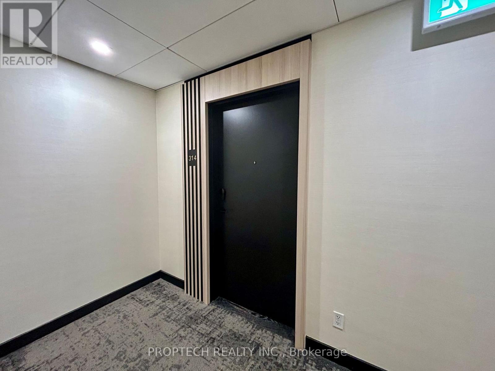 A black door with a wooden frame is in the middle of a room.