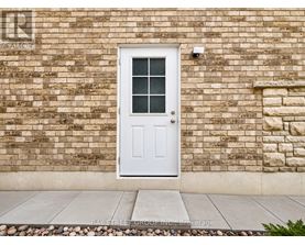 A white door with a glass window is set in a brick wall.