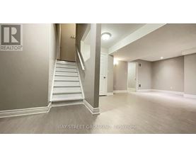 A spacious room with a staircase leading to another room.