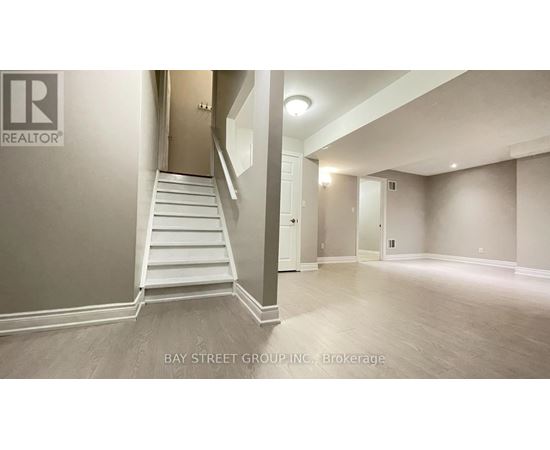 A spacious room with a staircase leading to another room.