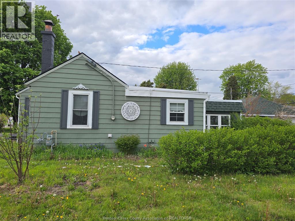 A green house with a white window and a white circular object on the wall.