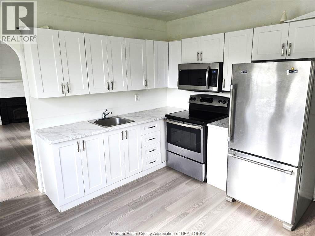 A kitchen with white cabinets and a stainless steel refrigerator.