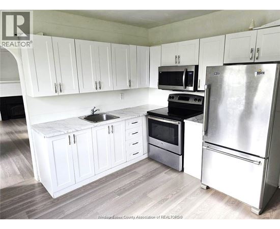 A kitchen with white cabinets and a stainless steel refrigerator.