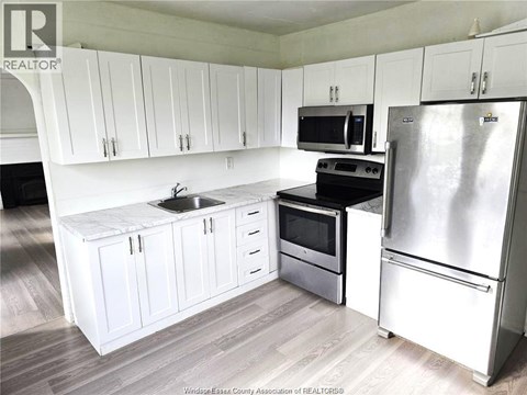 A kitchen with white cabinets and a stainless steel refrigerator.