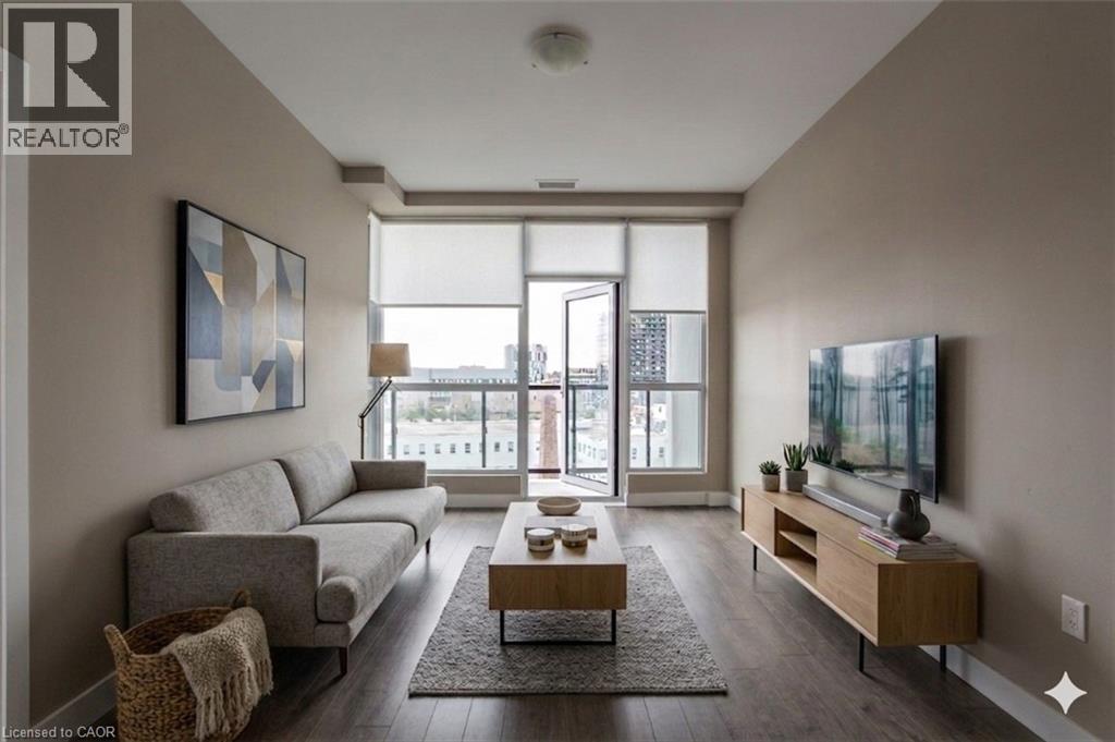A living room with a grey couch, a coffee table, and a large window.