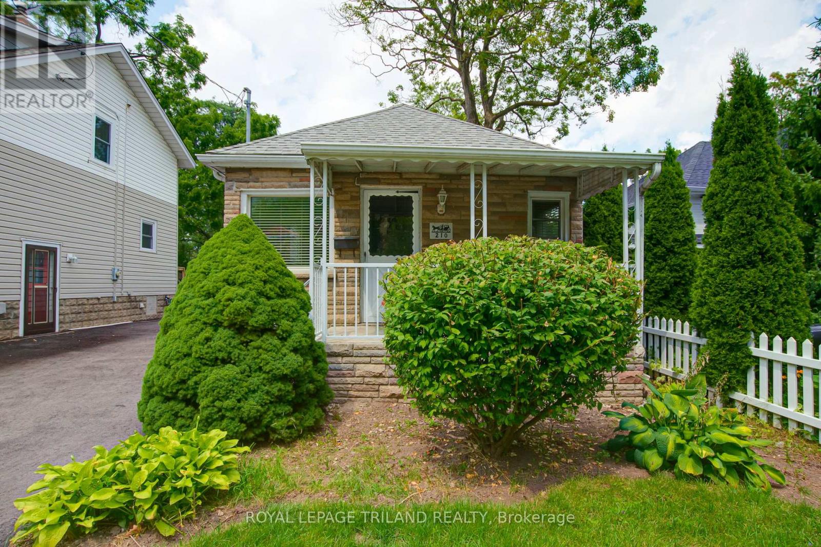 A house with a white picket fence and green bushes in front.