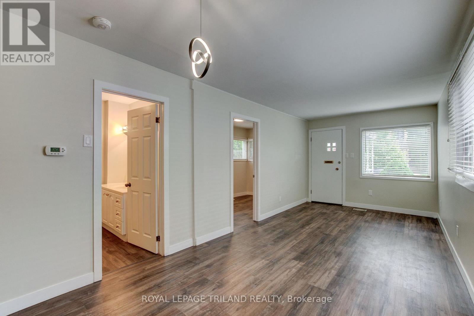 A spacious room with wooden flooring and white walls.