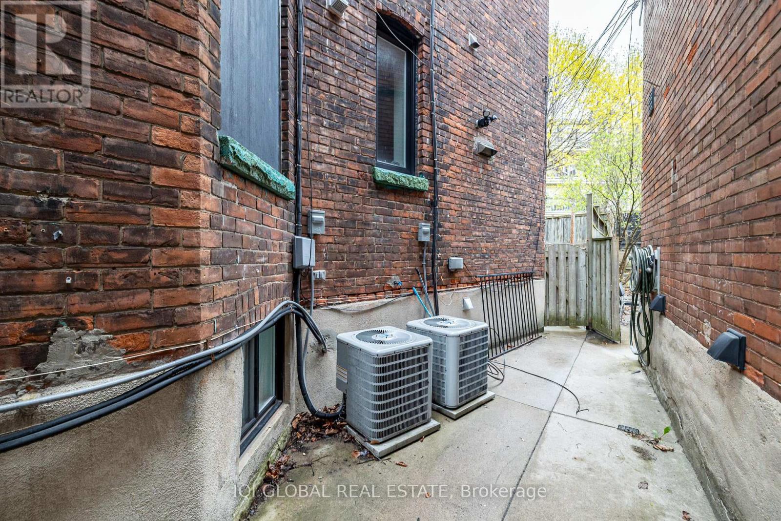 A narrow alley with two air conditioning units on the ground.