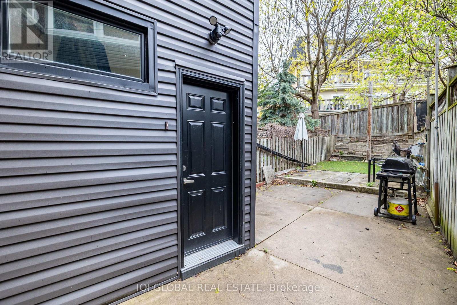 A black door is on a house with a small patio.