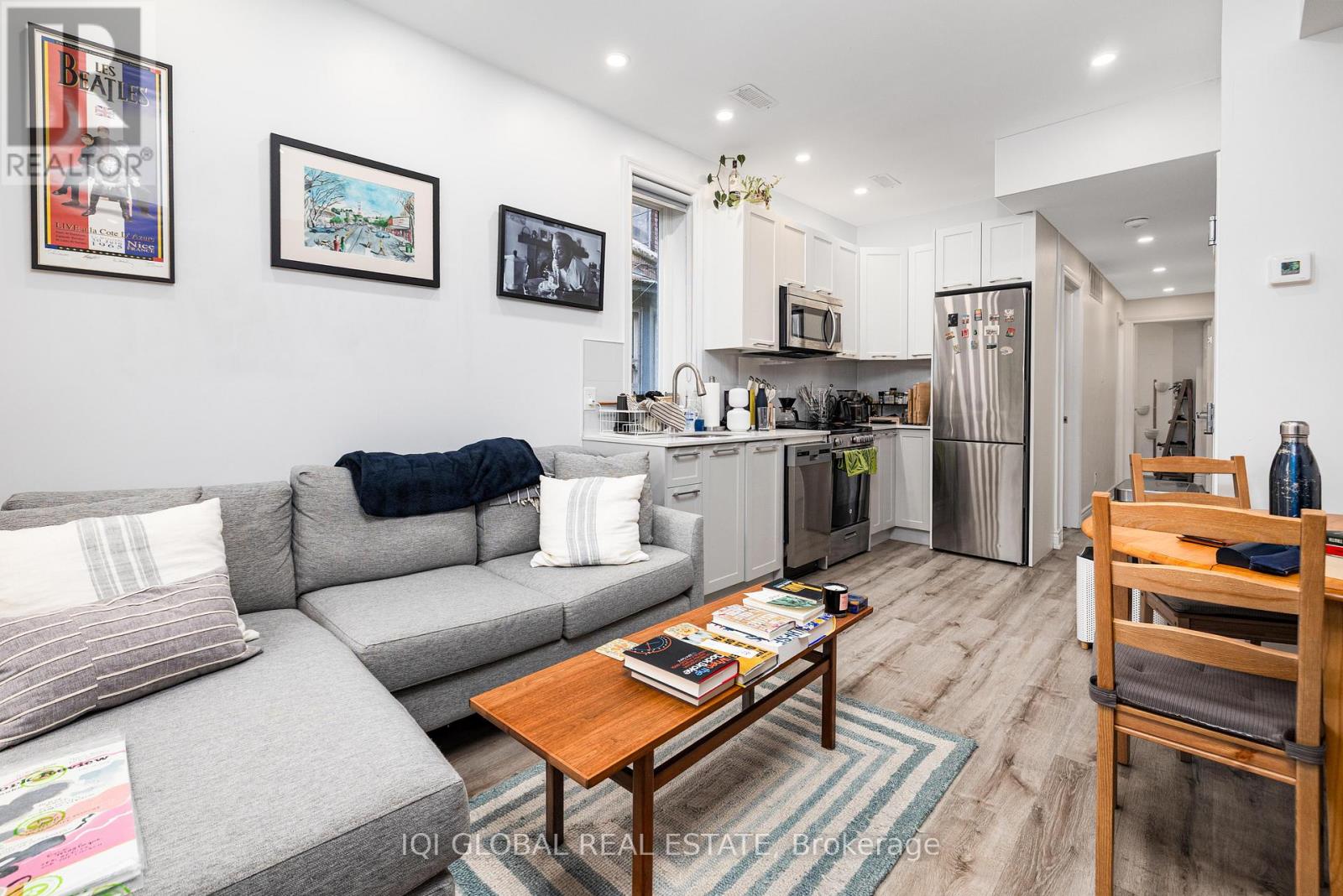 A modern living room with a grey sofa, a wooden coffee table, and a kitchen in the background.