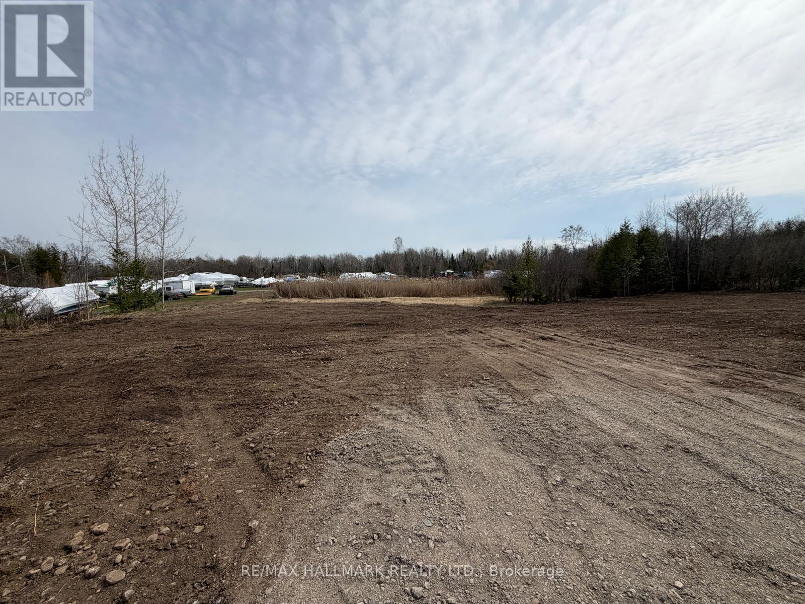 A large, empty plot of land with a dirt ground and sparse vegetation.
