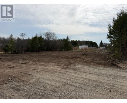 A dirt field with trees and a building in the distance.